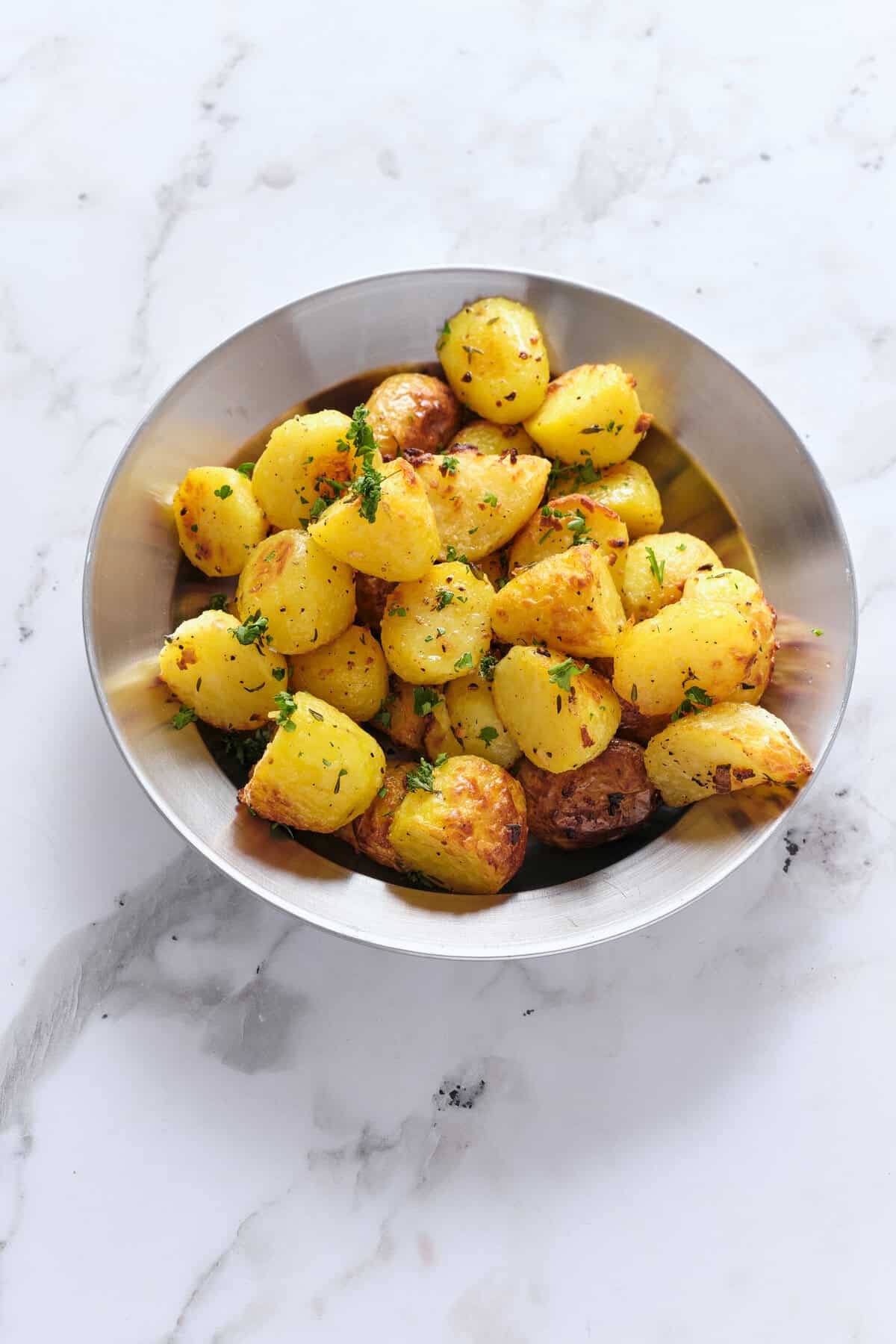 Golden roasted baby potatoes garnished with fresh herbs in a stainless steel bowl. Perfect for healthy meal ideas and nutritious side dishes, easy to make for a balanced diet.
