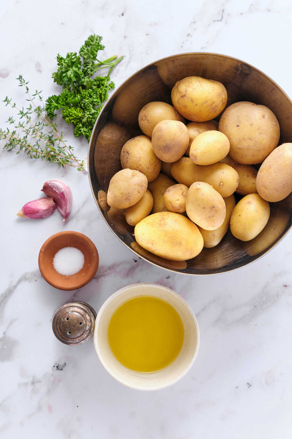 Fresh yellow potatoes with garlic, herbs, olive oil, and seasonings for healthy meal prep or recipe ideas; organic ingredients.