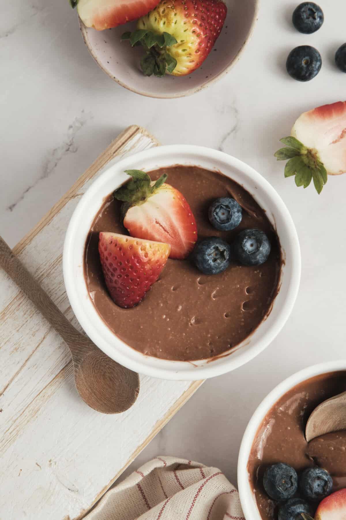 Creamy chocolate avocado mousse topped with fresh strawberries and blueberries, perfect for healthy dessert recipes and nutritious snacking.