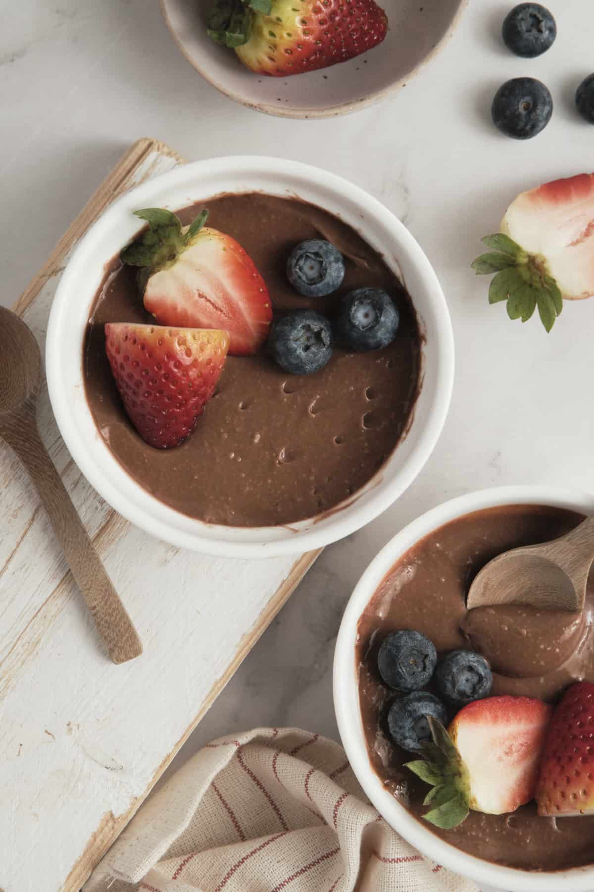 Rich chocolate avocado pudding topped with fresh strawberries and blueberries, perfect for healthy dessert recipes and guilt-free indulgence.