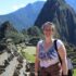Mountain landscape in Machu Picchu with tourist woman smiling and hiking, travel and adventure, historic Inca site, South America tourism, outdoor exploration.