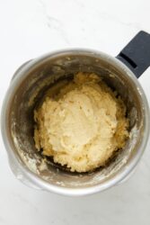 Creamy mashed potato mixture in a silver mixing bowl with a black handle, ready for cooking or further preparation, used in healthy recipes to support fitness and wellness goals.