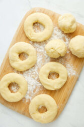 Buttery dough for homemade donuts on a wooden cutting board.