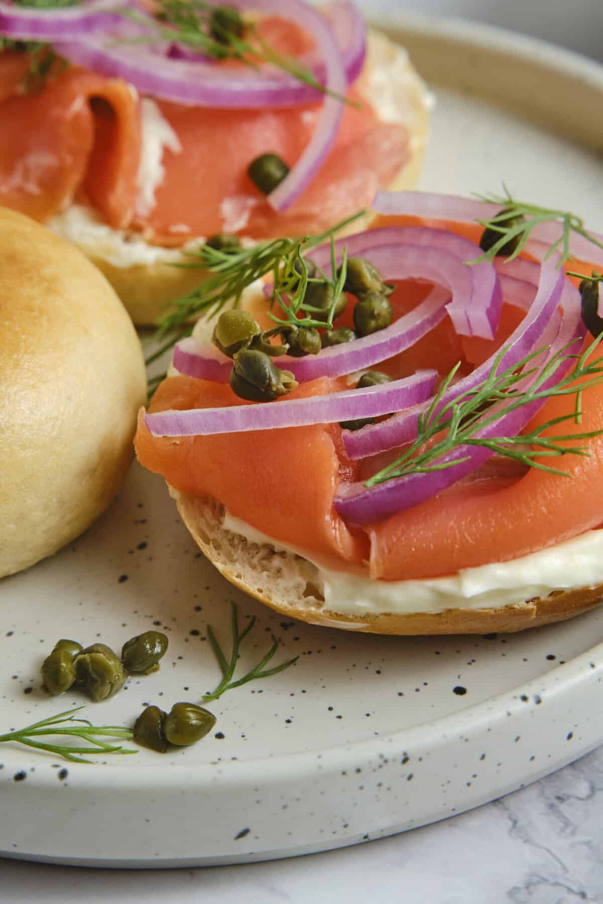 -Smoked Salmon Bagel with Red Onion, Capers, and Fresh Dill on a Light Plate.