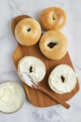 Fresh bagels with cream cheese on a wooden cutting board, healthy breakfast ideas, and bread recipes.