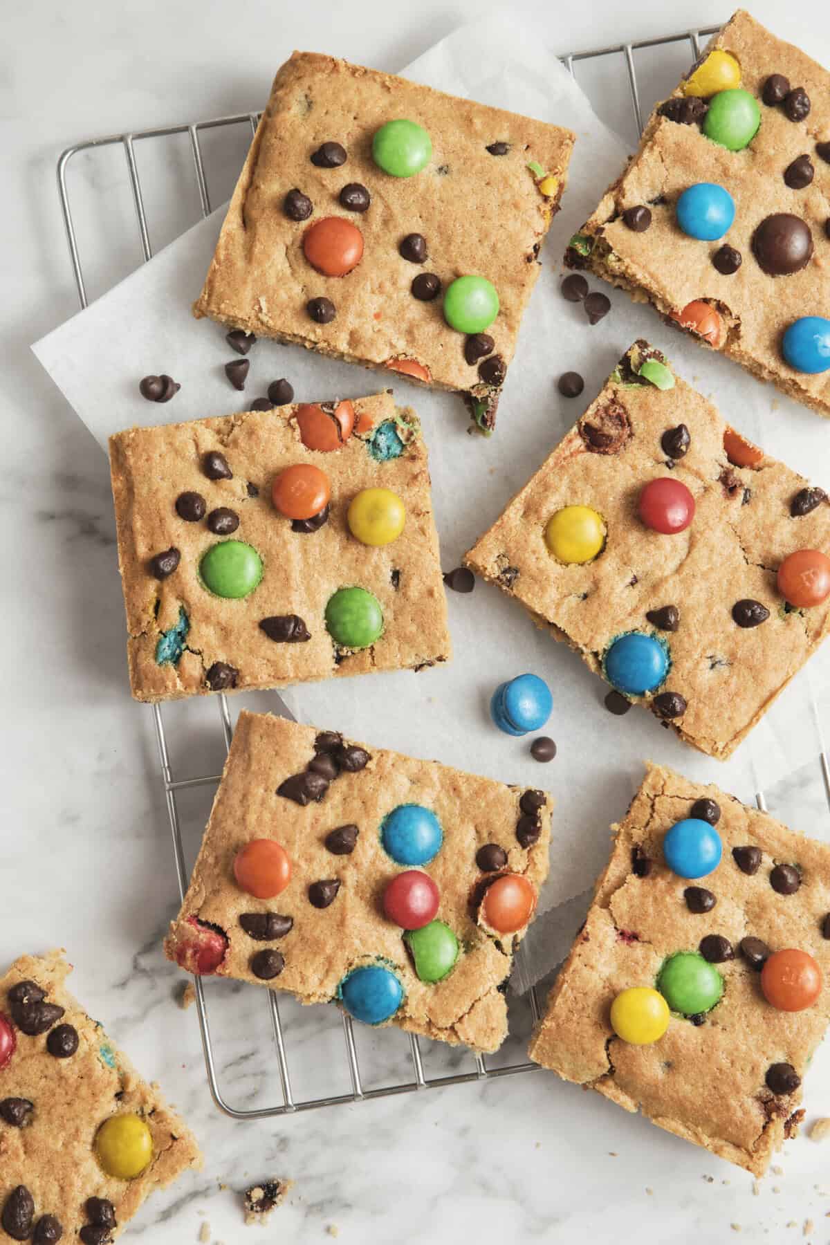 Butter cookie bars with colorful chocolate candies and chocolate chips on wire cooling rack, homemade dessert, easy cookie bar recipes, gluten-free treats, kid-friendly sweet snacks.