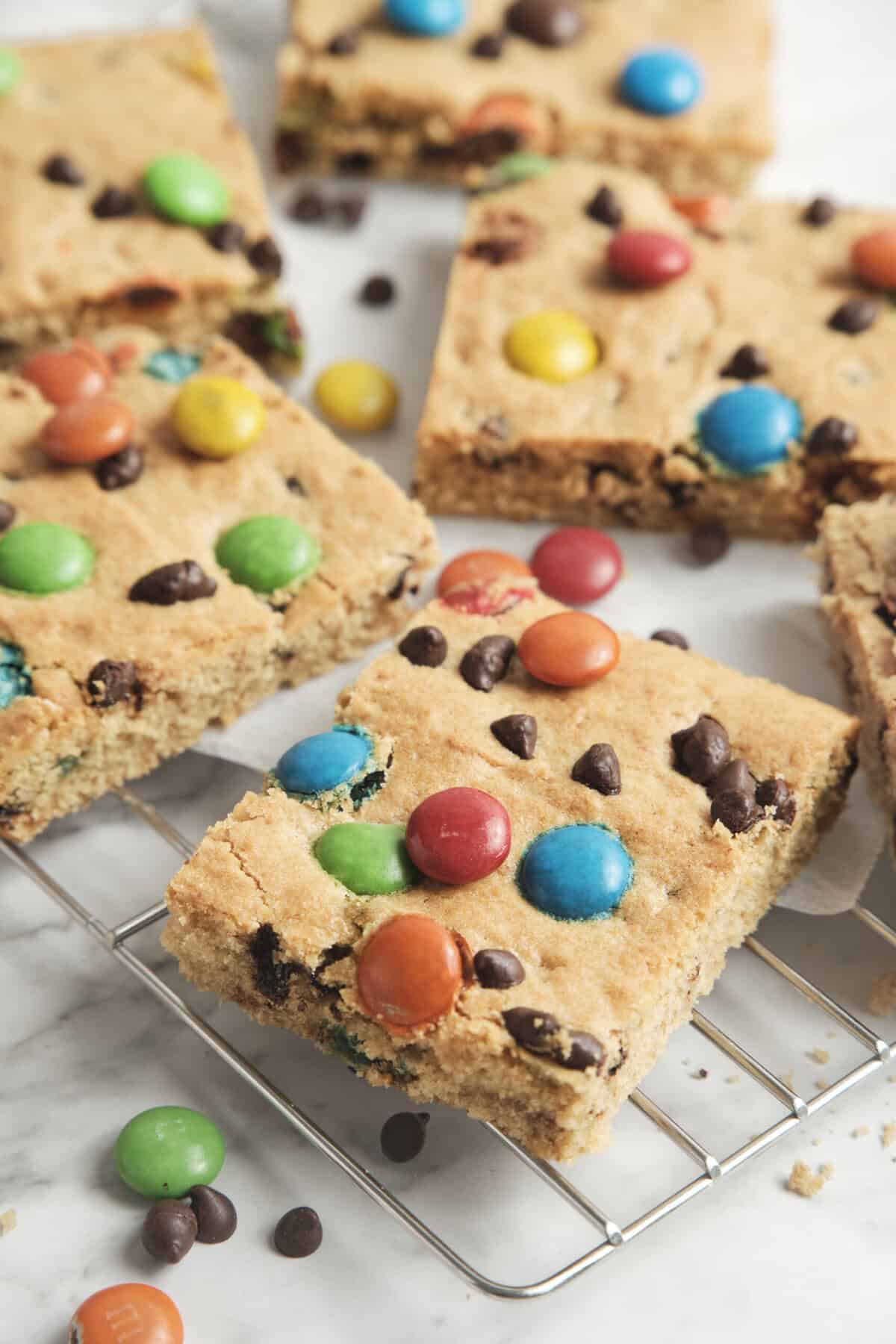 Colorful homemade granola bars with M&M candies and chocolate chips on cooling rack, healthy snack recipes, perfect for a balanced diet.
