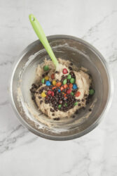 Creamy cookie dough batter with colorful chocolate chips and sprinkles in a metal mixing bowl on a marble surface, perfect for healthy dessert recipes on Food Faith Fitness.