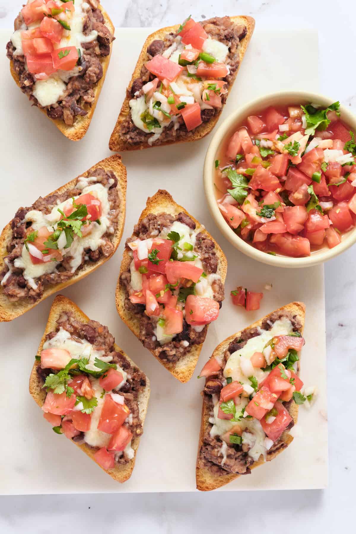 Scoop of seasoned ground beef with melted cheese and fresh pico de gallo on toasted bread slices, served with extra pico de gallo in a small bowl. Perfect for quick, healthy recipes and nutritious snack ideas.