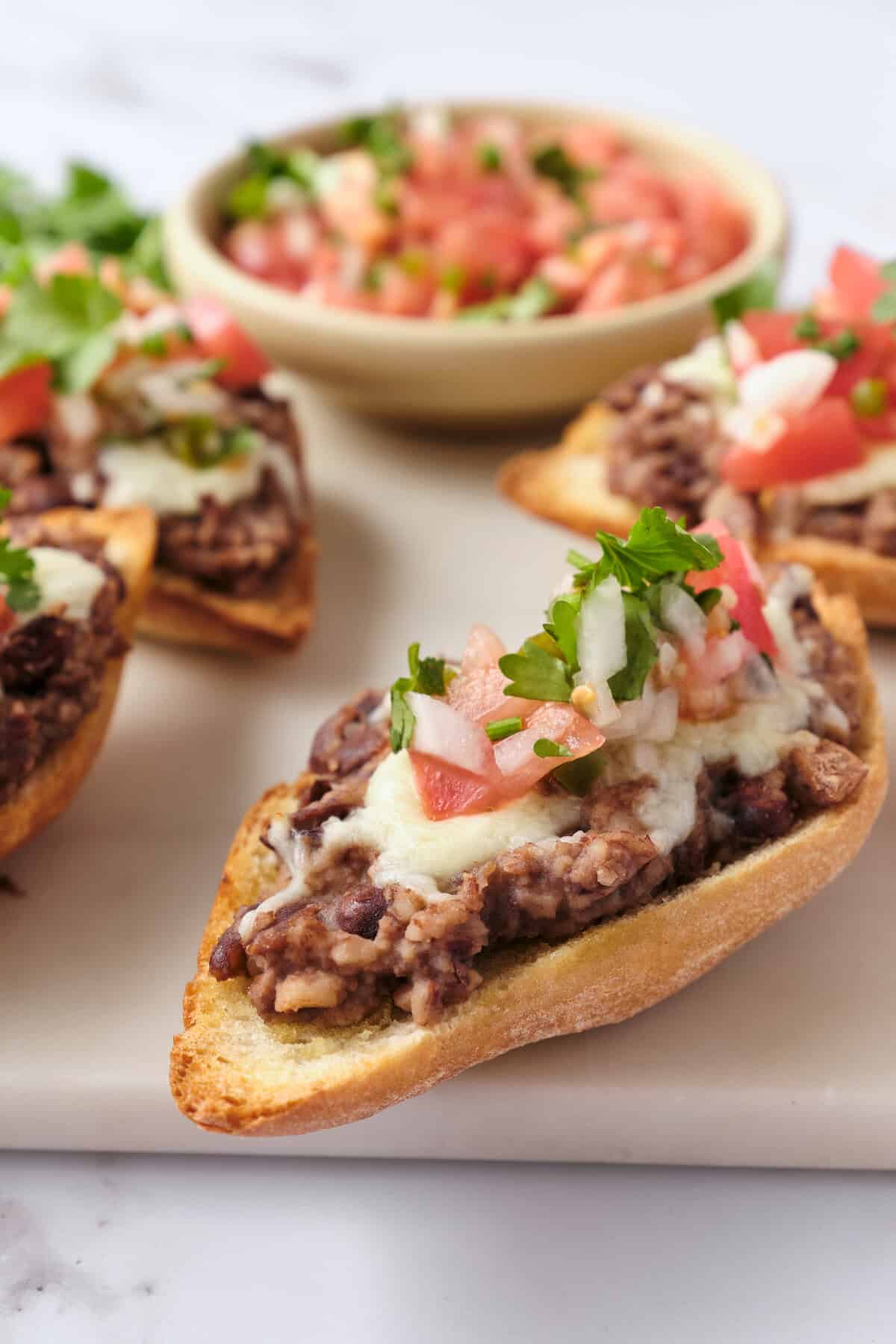 Savory beef and bean chili on toasted bread topped with fresh cilantro and diced tomatoes, served as a healthy and flavorful meal option on Food Faith Fitness website.