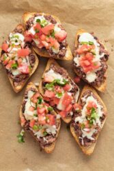 Savory beef and black bean nachos on crispy baguette slices topped with melted cheese, fresh tomatoes, and cilantro. Perfect healthy appetizer or snack from Food Faith Fitness.