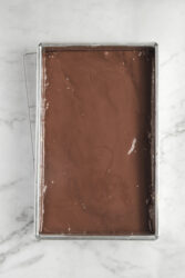Creamy homemade chocolate fudge in a rectangular metal baking pan, ready to set. Perfect healthy dessert or snack for food and fitness enthusiasts focusing on nutritious treats.