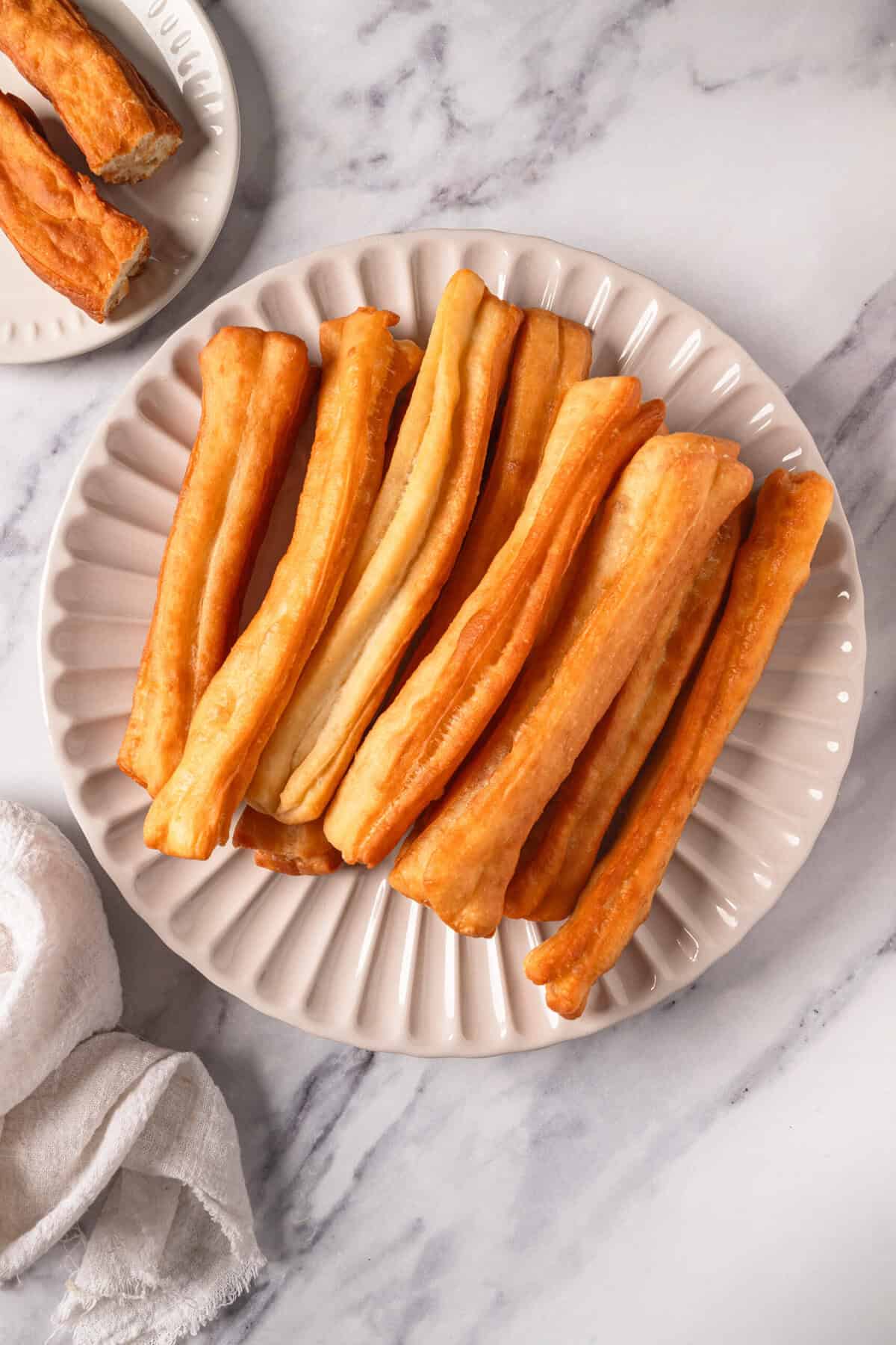 Crispy baked sweet potato fries served on a white scalloped plate, healthy snack or side dish, gluten-free, vegan-friendly, perfect for nutritious eating and meal prep.