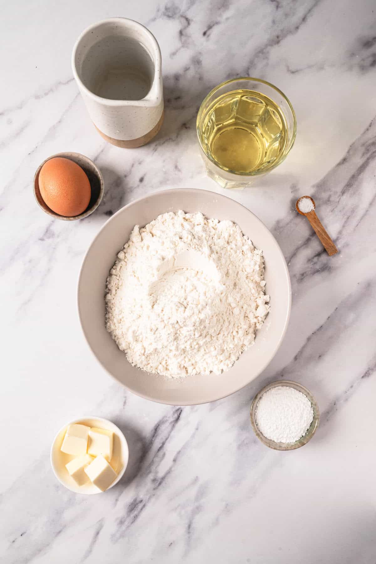 Flour, eggs, butter, oil, and baking ingredients on marble countertop for healthy baking recipes at Food Faith Fitness.